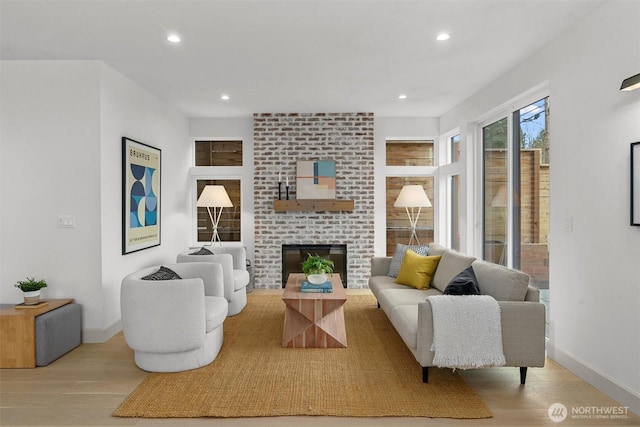 living area featuring a brick fireplace, wood finished floors, and recessed lighting