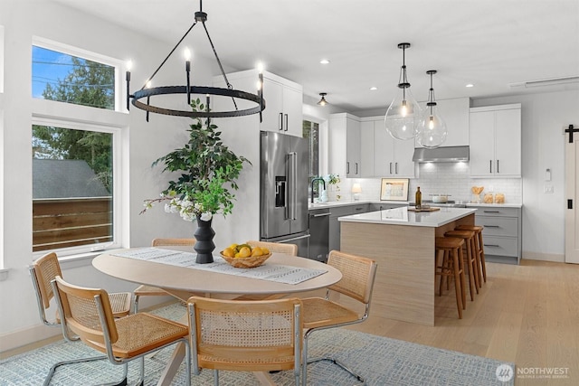 kitchen with high end refrigerator, decorative backsplash, a kitchen island, light countertops, and under cabinet range hood