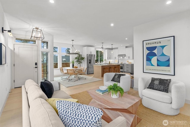 living area with light wood-style floors, recessed lighting, and an inviting chandelier