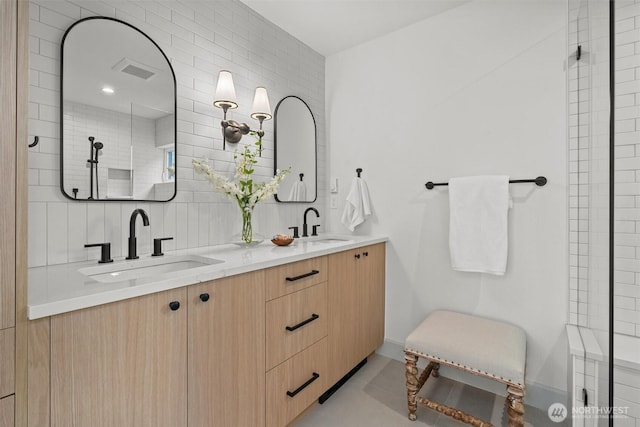 bathroom featuring visible vents, a sink, decorative backsplash, and double vanity