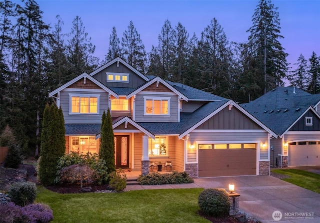 craftsman inspired home featuring a yard, an attached garage, board and batten siding, stone siding, and driveway