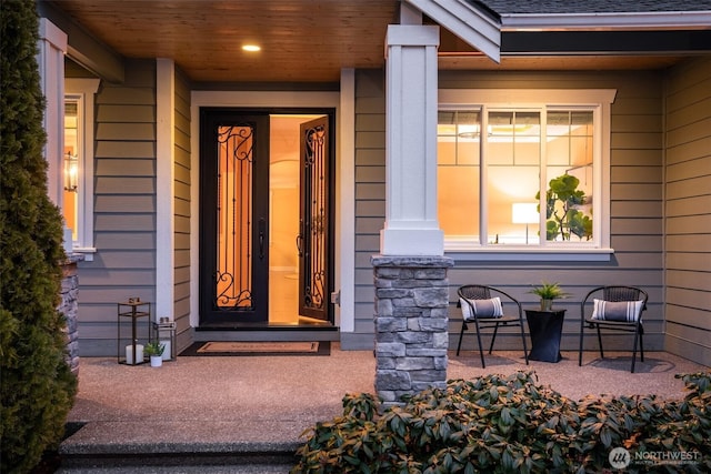 view of exterior entry featuring a porch and roof with shingles