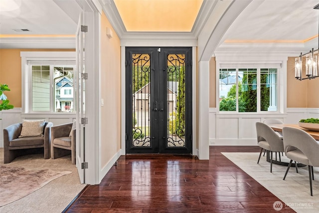 entrance foyer featuring a healthy amount of sunlight, visible vents, wood finished floors, and ornamental molding