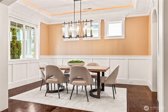 dining room with crown molding, a raised ceiling, and dark wood finished floors