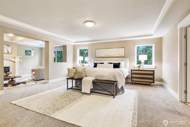 bedroom featuring carpet floors, a tray ceiling, a tiled fireplace, and baseboards