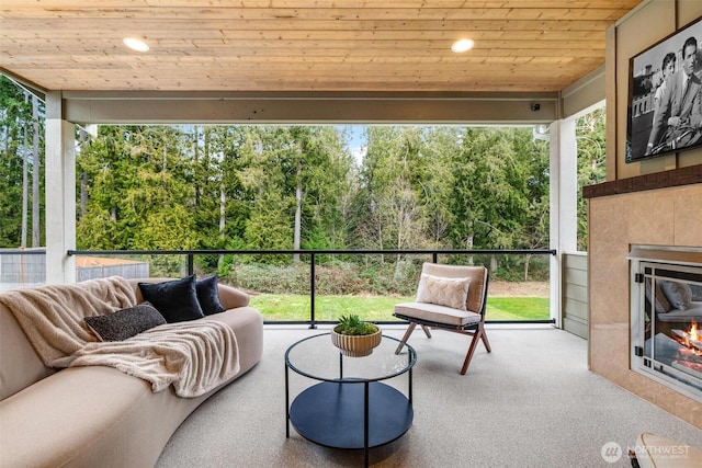 sunroom featuring wood ceiling, a healthy amount of sunlight, and a tiled fireplace