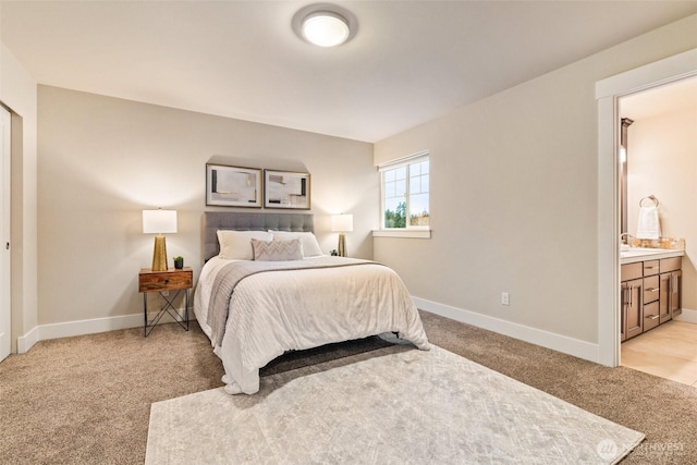 bedroom featuring baseboards, connected bathroom, and light colored carpet