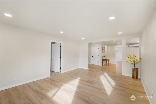 spare room with a wall mounted AC and light hardwood / wood-style floors