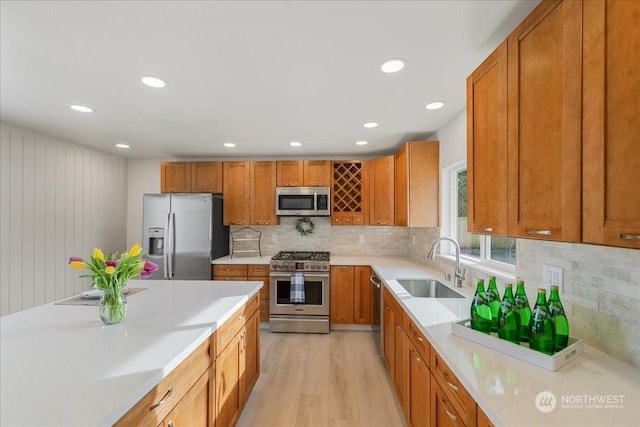 kitchen featuring sink, backsplash, light hardwood / wood-style floors, and appliances with stainless steel finishes