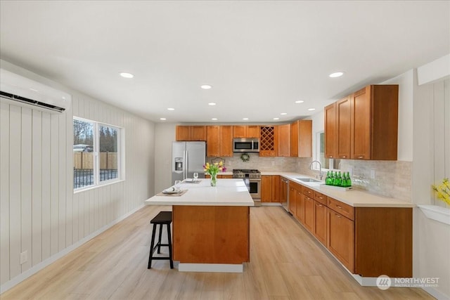 kitchen with sink, appliances with stainless steel finishes, a center island, light hardwood / wood-style floors, and a kitchen bar