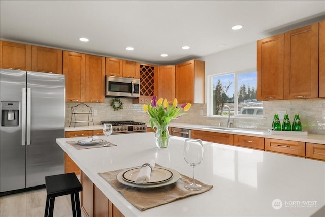 kitchen featuring sink, a breakfast bar, stainless steel appliances, tasteful backsplash, and light hardwood / wood-style floors