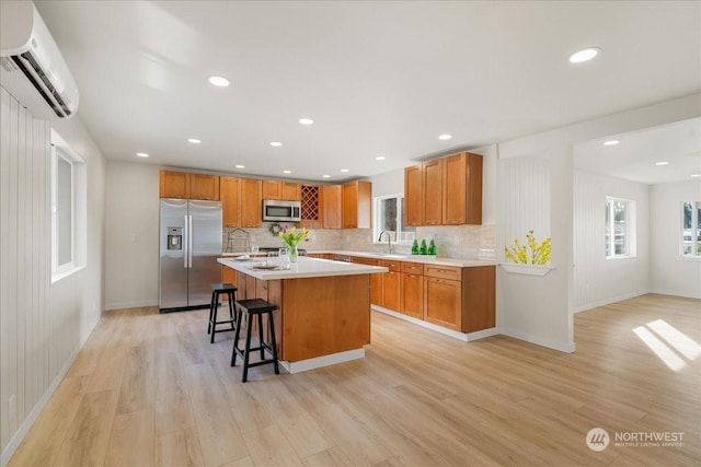 kitchen with a kitchen island, appliances with stainless steel finishes, a breakfast bar, light wood-type flooring, and a wall unit AC