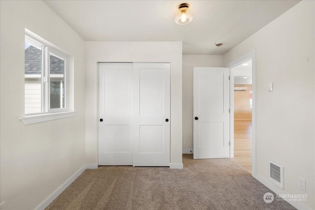 unfurnished bedroom featuring a closet and light carpet