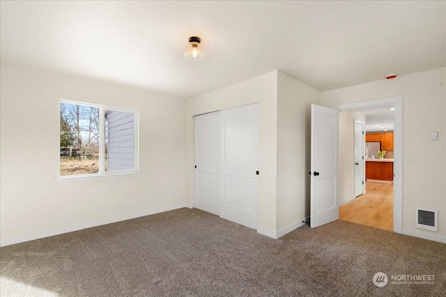 unfurnished bedroom with carpet flooring, stainless steel refrigerator, and a closet