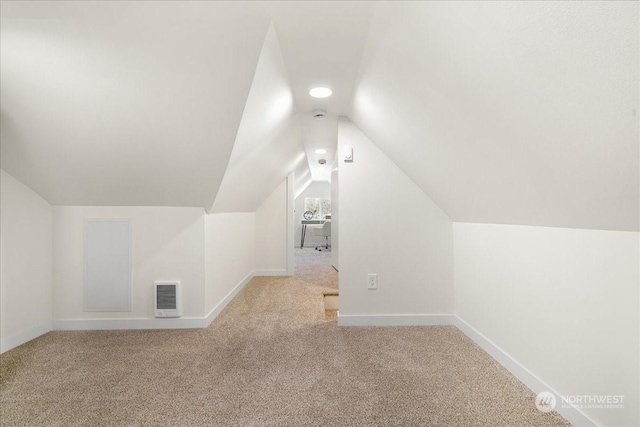 additional living space with lofted ceiling, heating unit, and light carpet