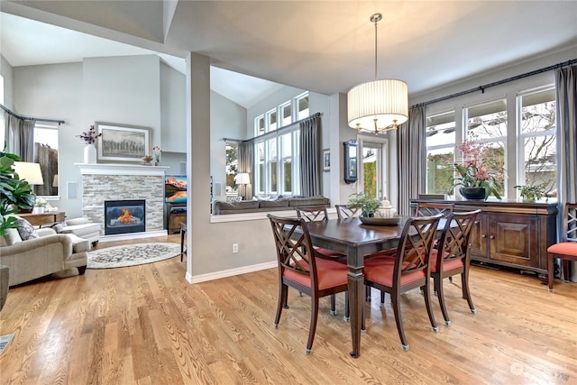 dining area with lofted ceiling, a fireplace, and light hardwood / wood-style flooring