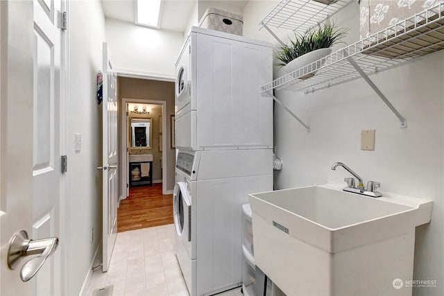 laundry area featuring stacked washer / drying machine and sink