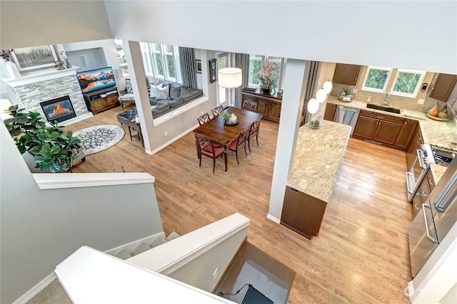 living room featuring a stone fireplace, sink, and light hardwood / wood-style flooring