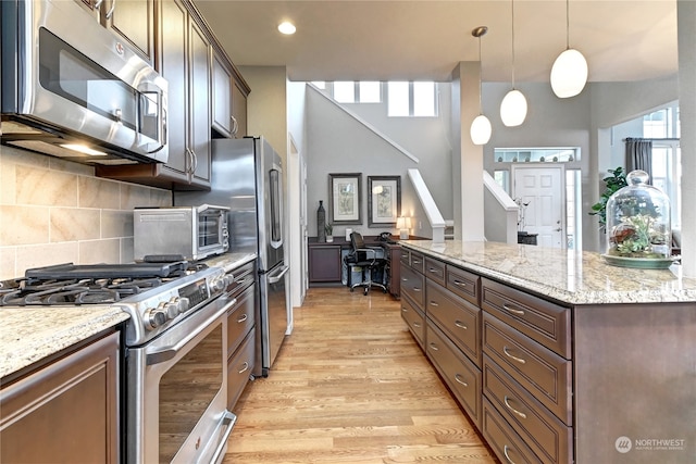 kitchen featuring hanging light fixtures, appliances with stainless steel finishes, dark brown cabinets, and light hardwood / wood-style floors