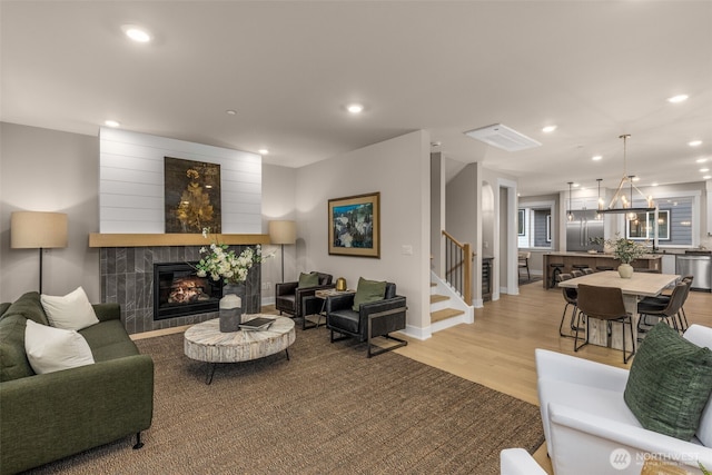 living room with light wood-style flooring, recessed lighting, stairway, and a tiled fireplace