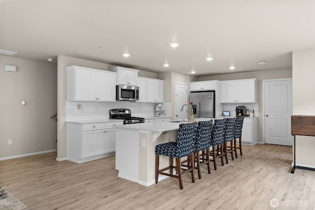kitchen with light wood-type flooring, a sink, backsplash, and stainless steel appliances