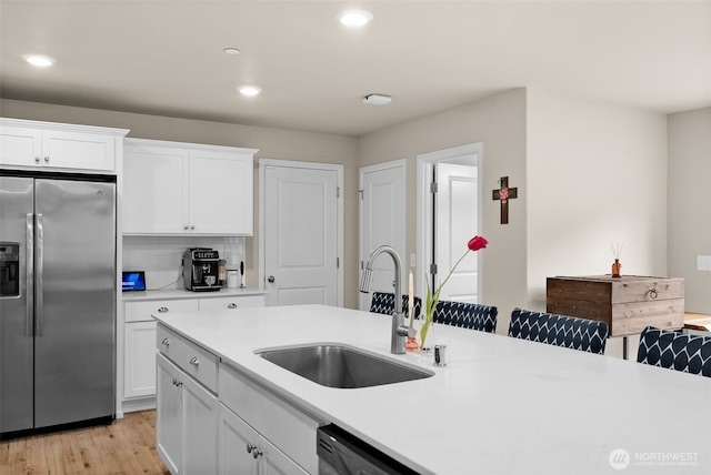 kitchen with light countertops, stainless steel refrigerator with ice dispenser, recessed lighting, and a sink