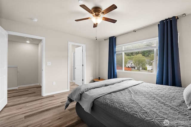 bedroom featuring baseboards, ceiling fan, wood finished floors, and ensuite bath