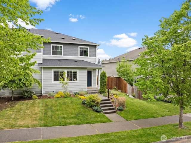 traditional-style house with a front lawn, roof with shingles, and fence
