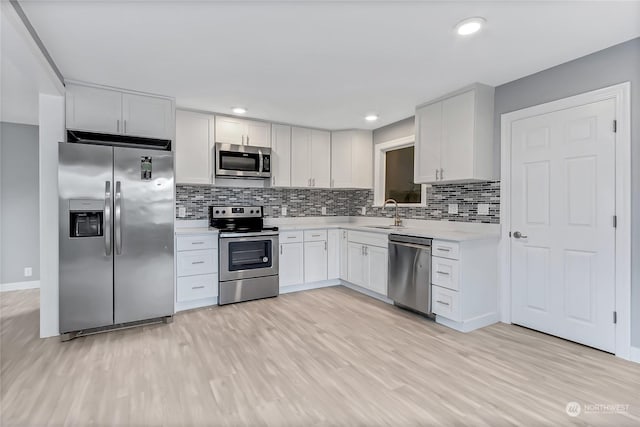 kitchen with stainless steel appliances, light hardwood / wood-style flooring, and white cabinets