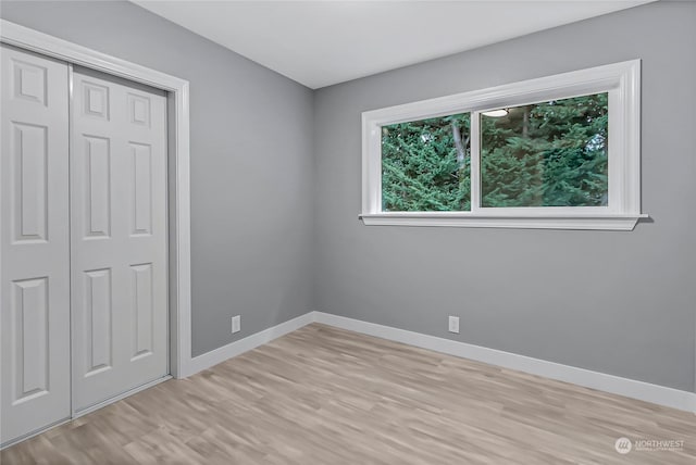 unfurnished bedroom featuring light wood-type flooring and a closet
