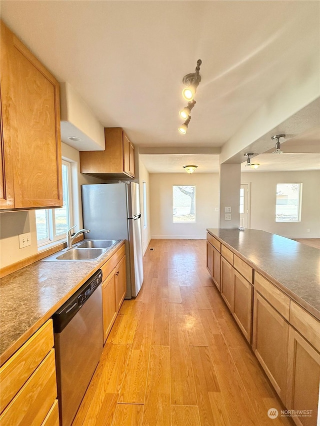 kitchen with appliances with stainless steel finishes, sink, and light hardwood / wood-style floors