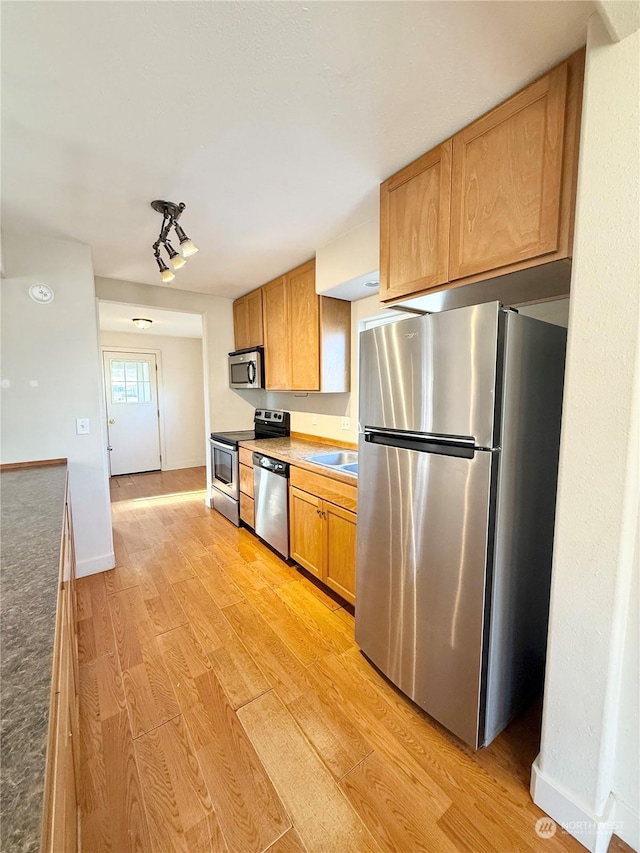 kitchen featuring stainless steel appliances, sink, and light hardwood / wood-style floors