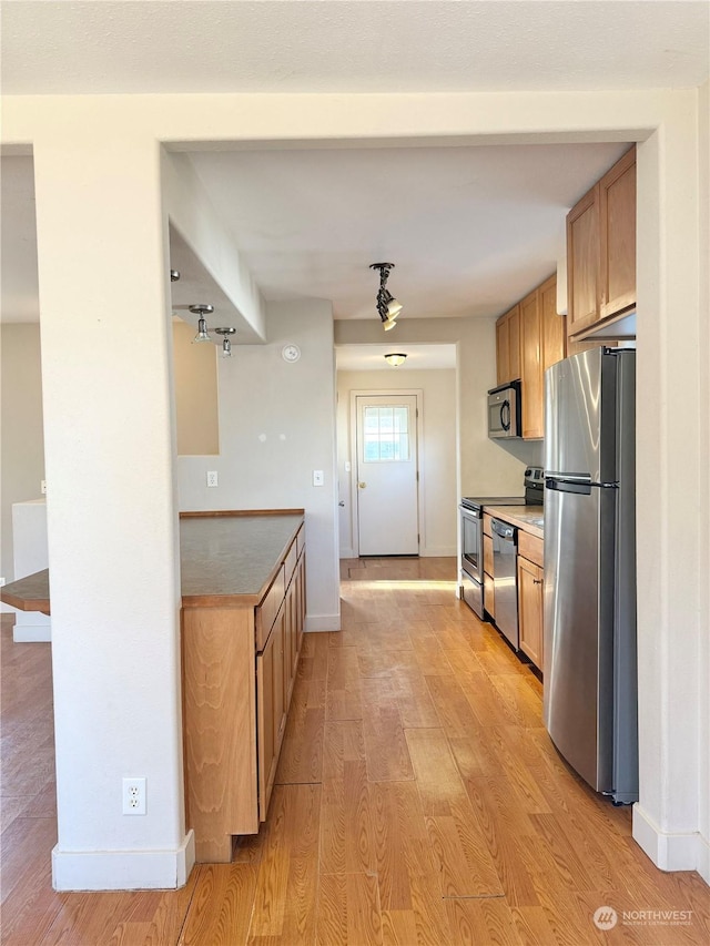 kitchen with light brown cabinetry, light wood-type flooring, and appliances with stainless steel finishes