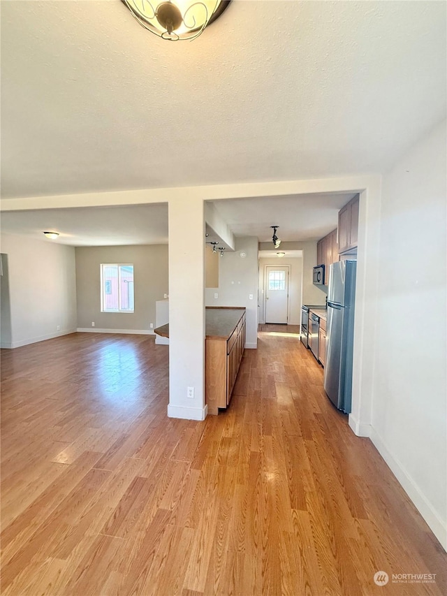 kitchen featuring kitchen peninsula, a textured ceiling, stainless steel refrigerator, and light hardwood / wood-style flooring