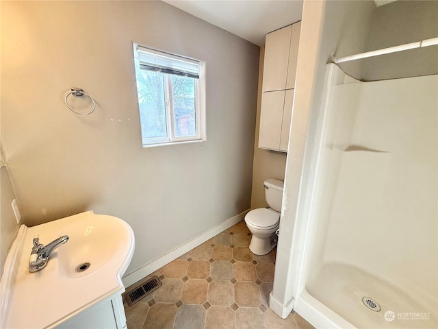 bathroom featuring tile patterned floors, vanity, toilet, and a shower