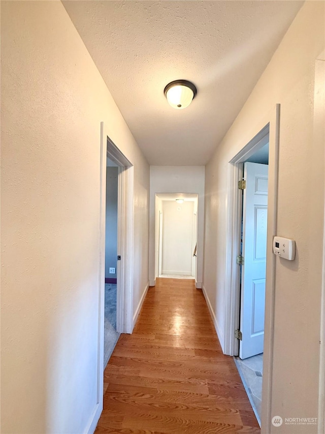 hall with wood-type flooring and a textured ceiling