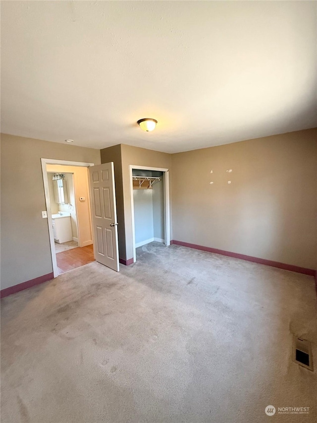 unfurnished bedroom featuring light colored carpet and a closet