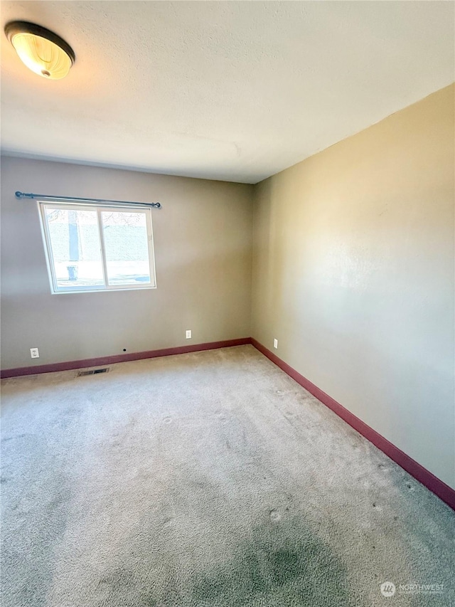 carpeted spare room with a textured ceiling