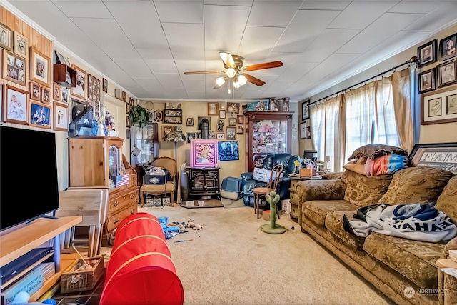 carpeted living room featuring crown molding, a wood stove, and ceiling fan