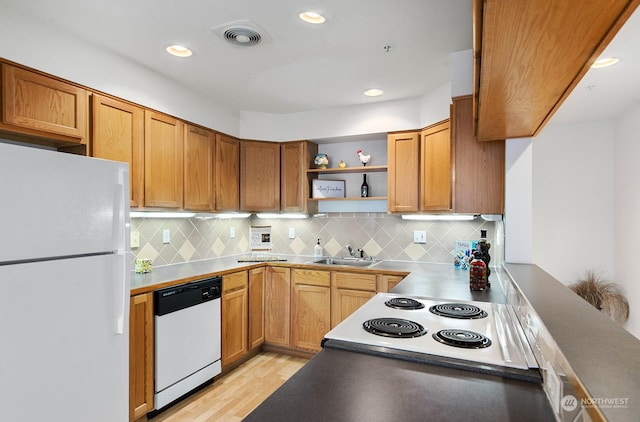 kitchen with tasteful backsplash, white appliances, sink, and light hardwood / wood-style flooring