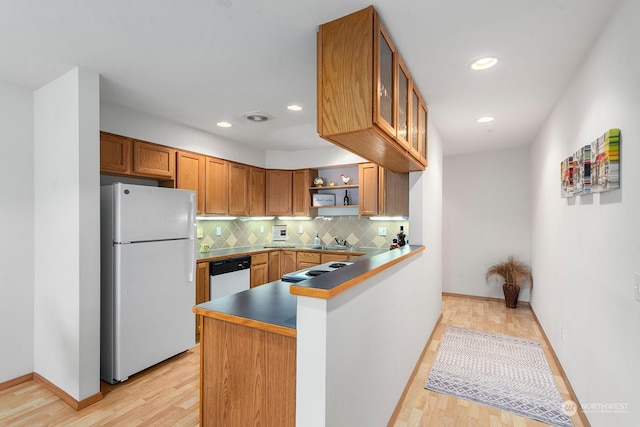 kitchen featuring white refrigerator, dishwasher, light wood-type flooring, and kitchen peninsula