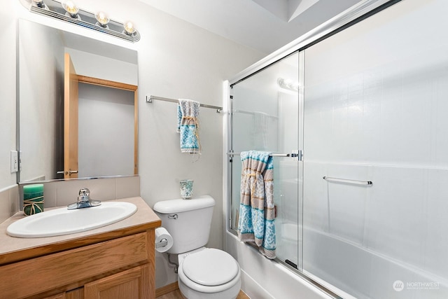 full bathroom featuring toilet, vanity, and bath / shower combo with glass door