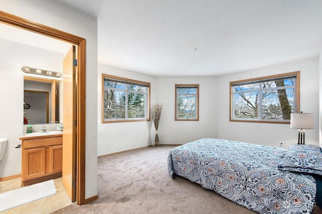 carpeted bedroom featuring sink and ensuite bath