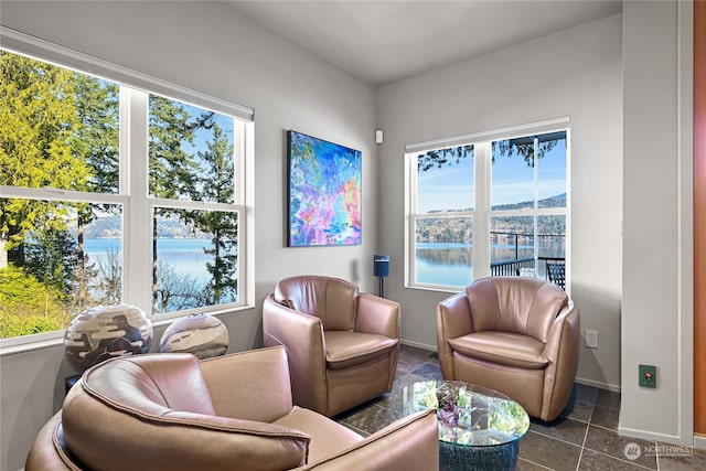 sitting room with a water view and dark tile patterned flooring
