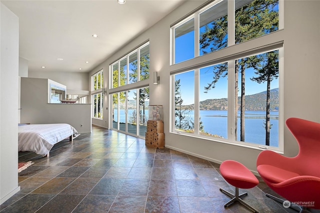 bedroom featuring a water view and a high ceiling