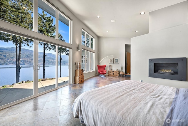bedroom with a water and mountain view, tile patterned flooring, access to outside, and a high ceiling