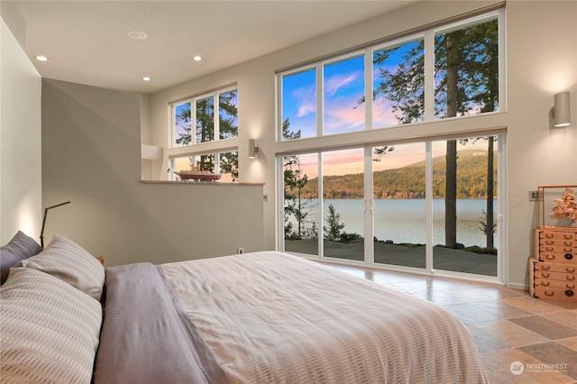 bedroom with a water view, access to outside, and a towering ceiling