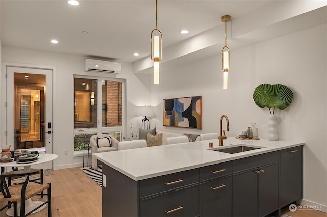 kitchen with hanging light fixtures, sink, a wall unit AC, and kitchen peninsula