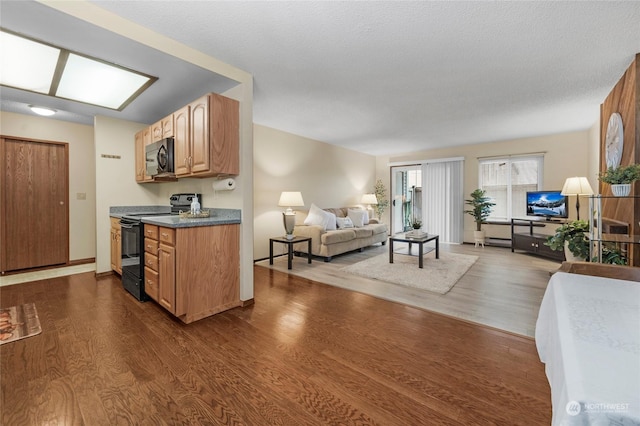 kitchen featuring dark wood-type flooring, black appliances, and a textured ceiling