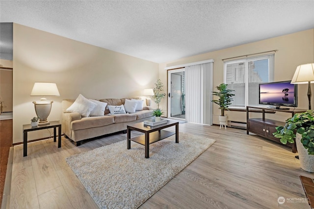 living room featuring a baseboard heating unit, a textured ceiling, and light hardwood / wood-style floors